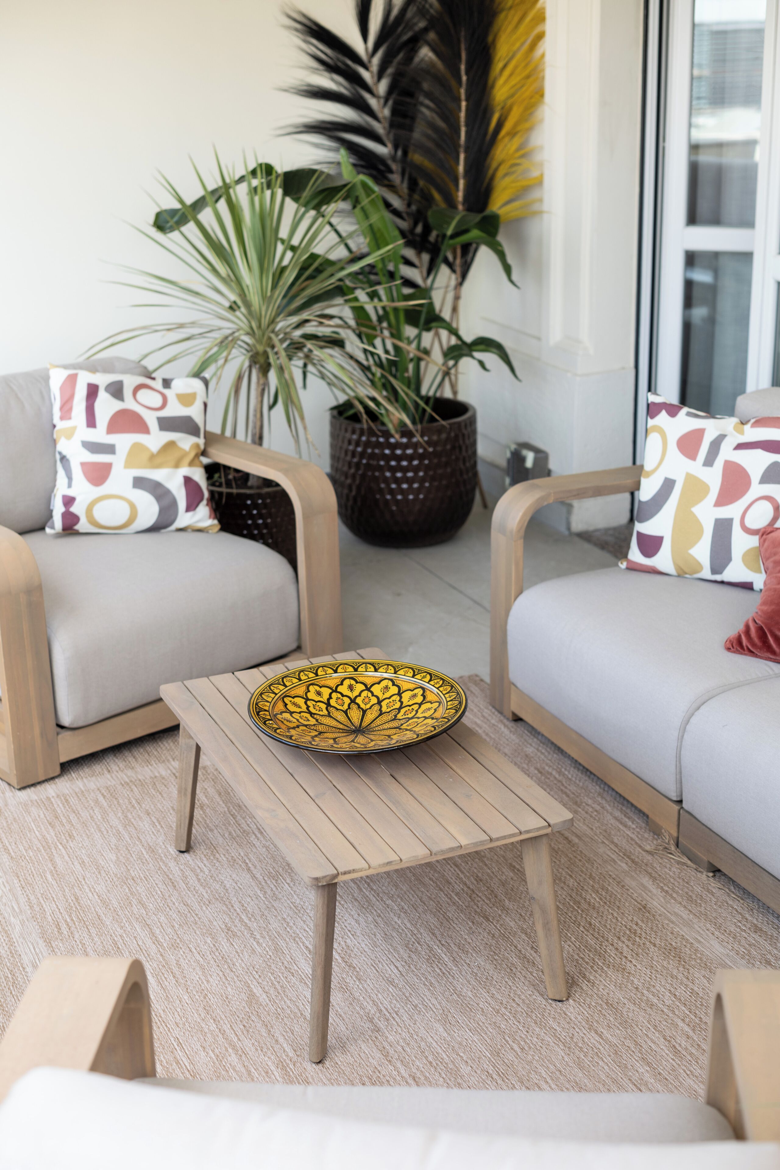 A modern living room with two sofas, a coffee table, and a large potted plant.