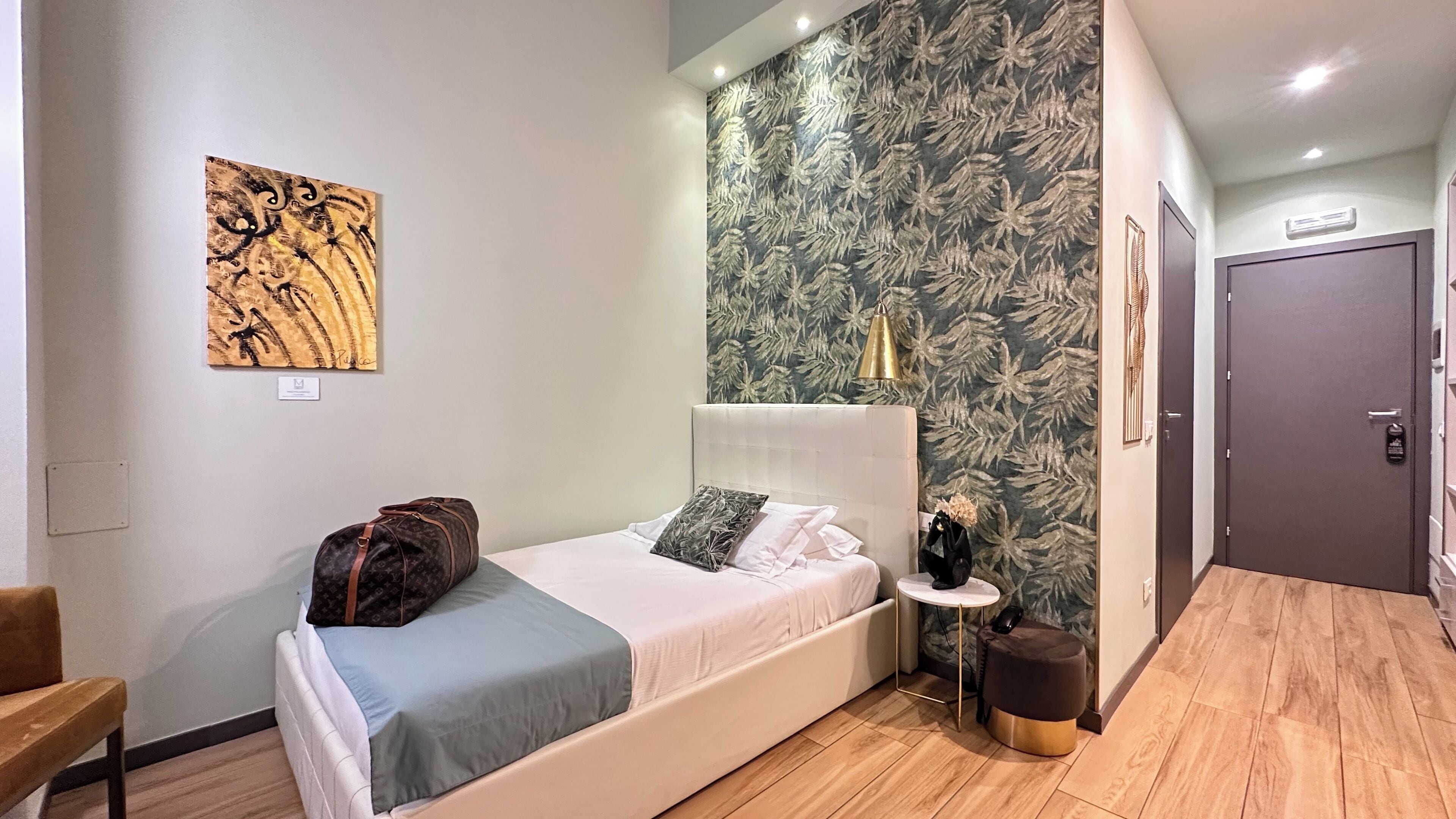 Une chambre à coucher moderne avec un lit, une petite table de chevet, une œuvre d’art murale et une porte.