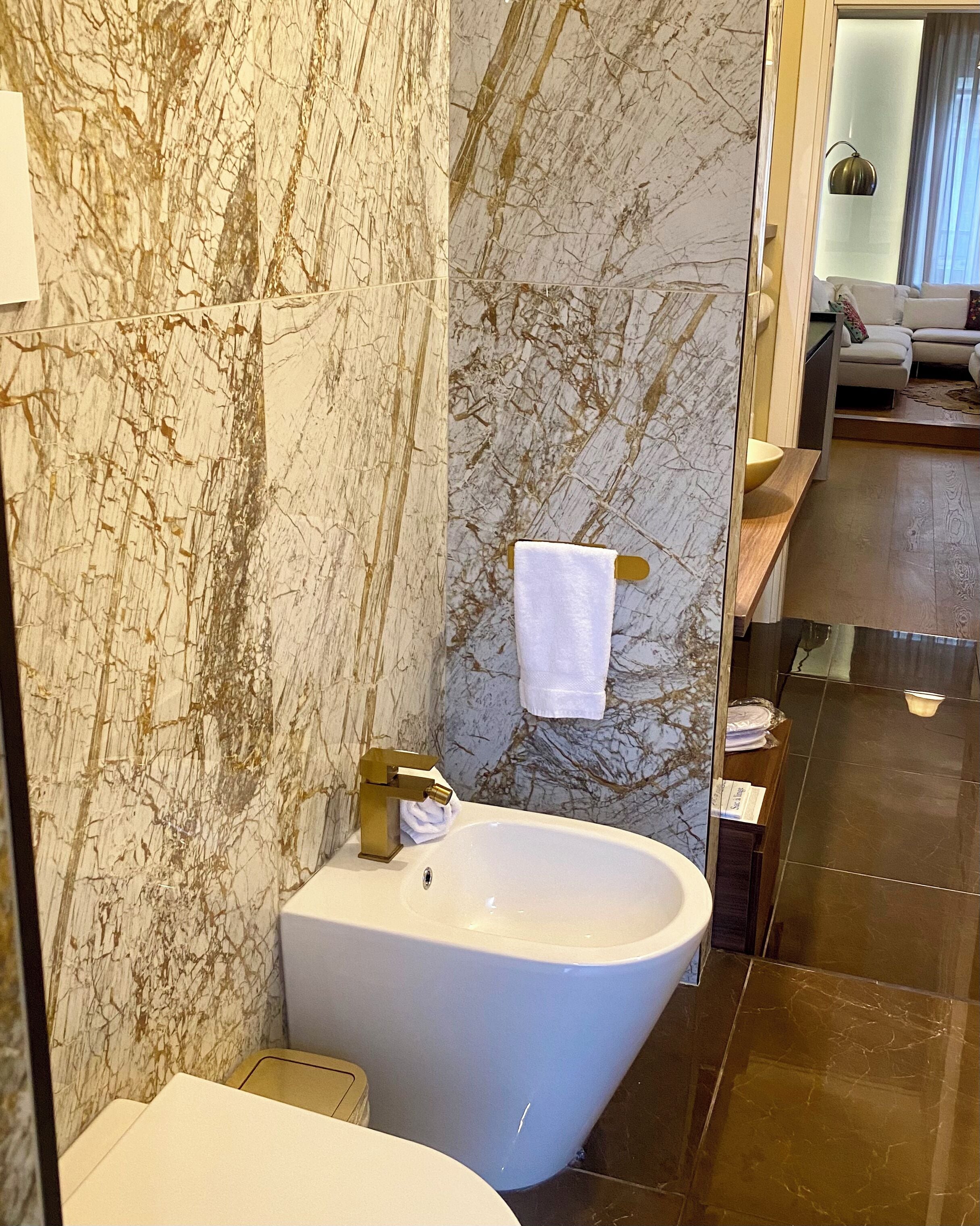 Un baño con una bañera independiente, paredes de mármol y una toalla colgada en un perchero.