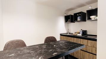 A modern kitchen with a marble countertop, wooden cabinets, and a black chair.