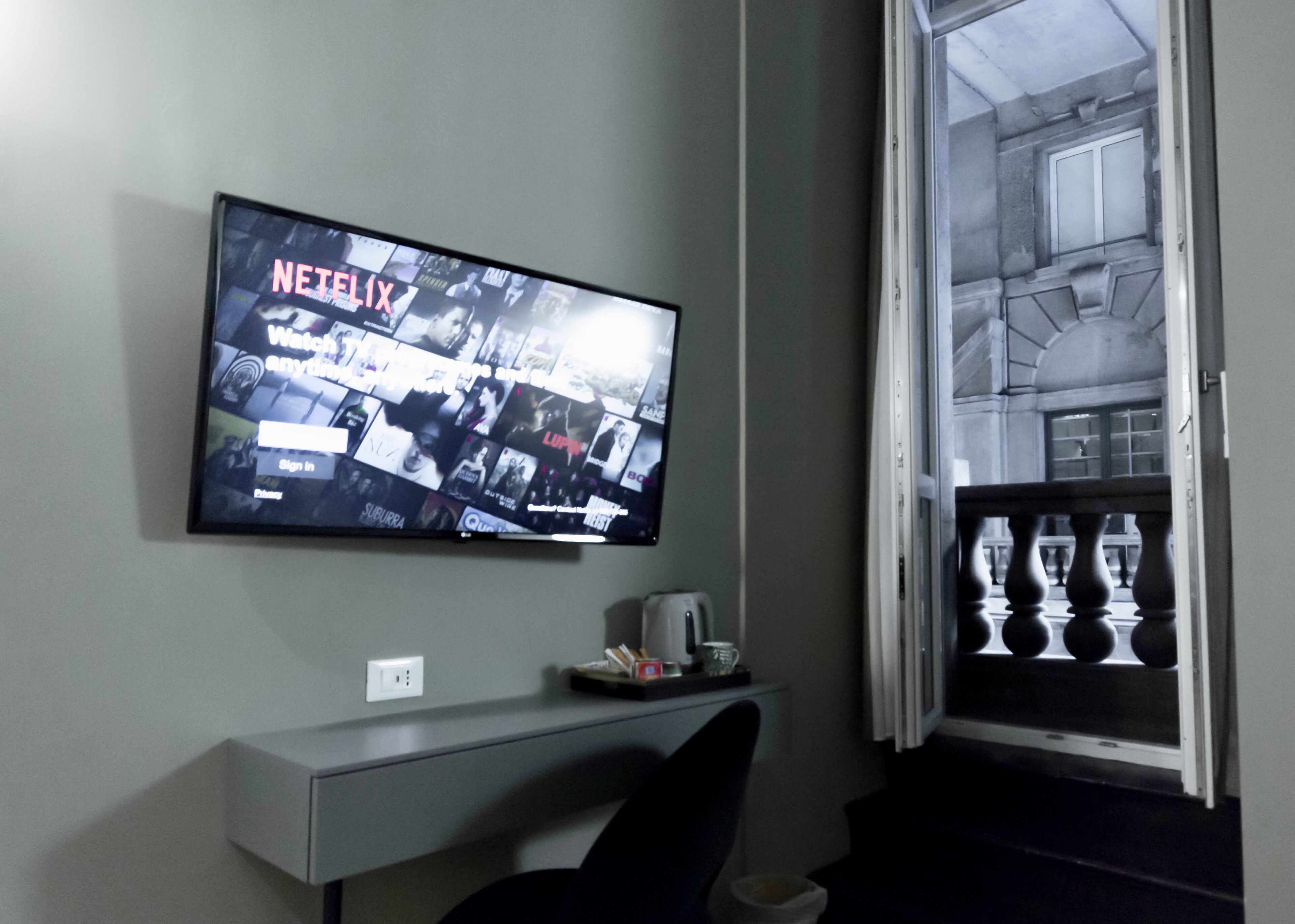 Een flatscreen-tv aan een muur, waarop een Netflix-interface wordt weergegeven.