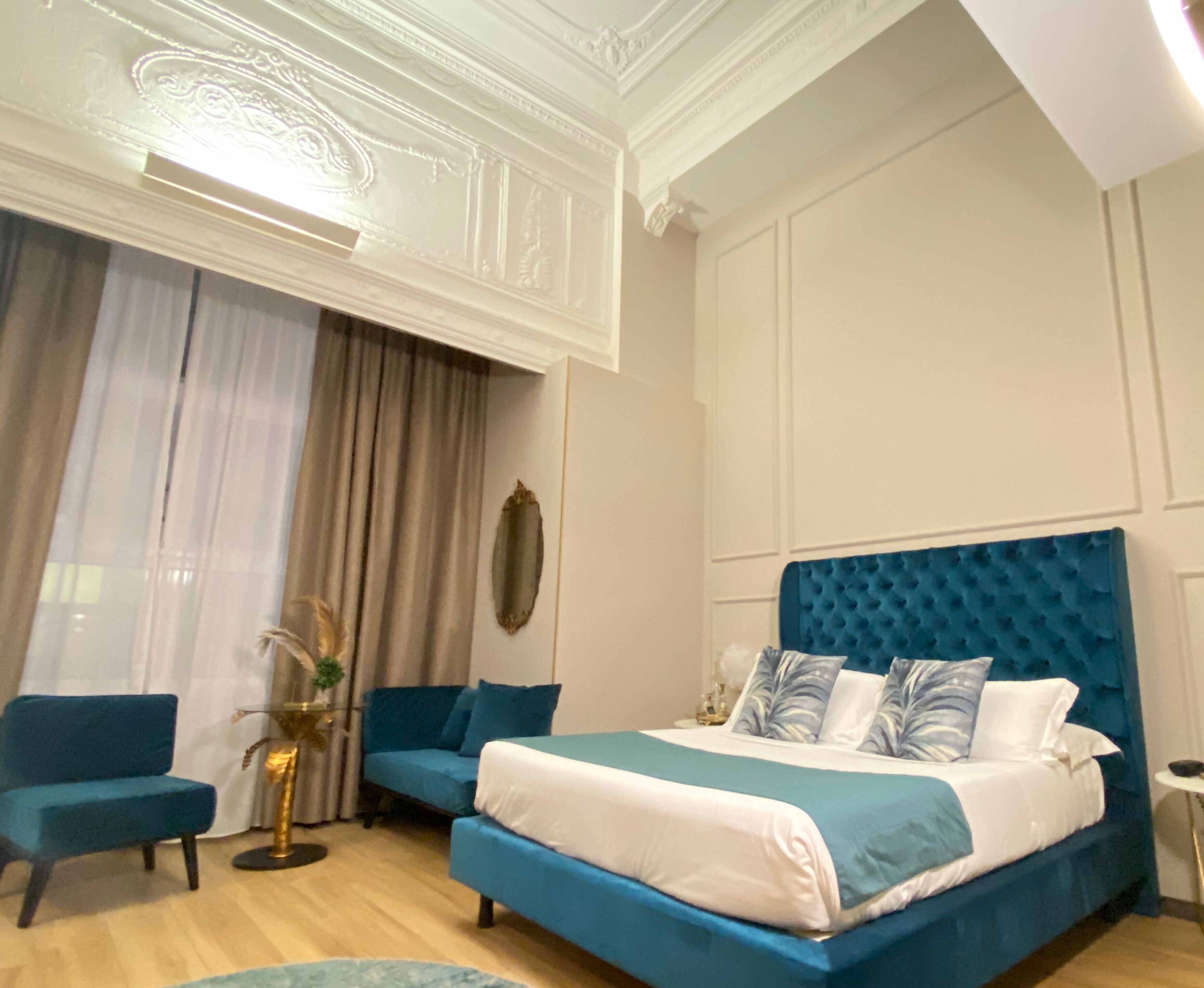 Ein Schlafzimmer mit einem großen Bett, einem blauen Kopfteil, einem blauen Sofa und einem kleinen runden Tisch.