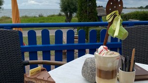 Una mesa con una porción de pastel, una bebida de postre y una cuchara.