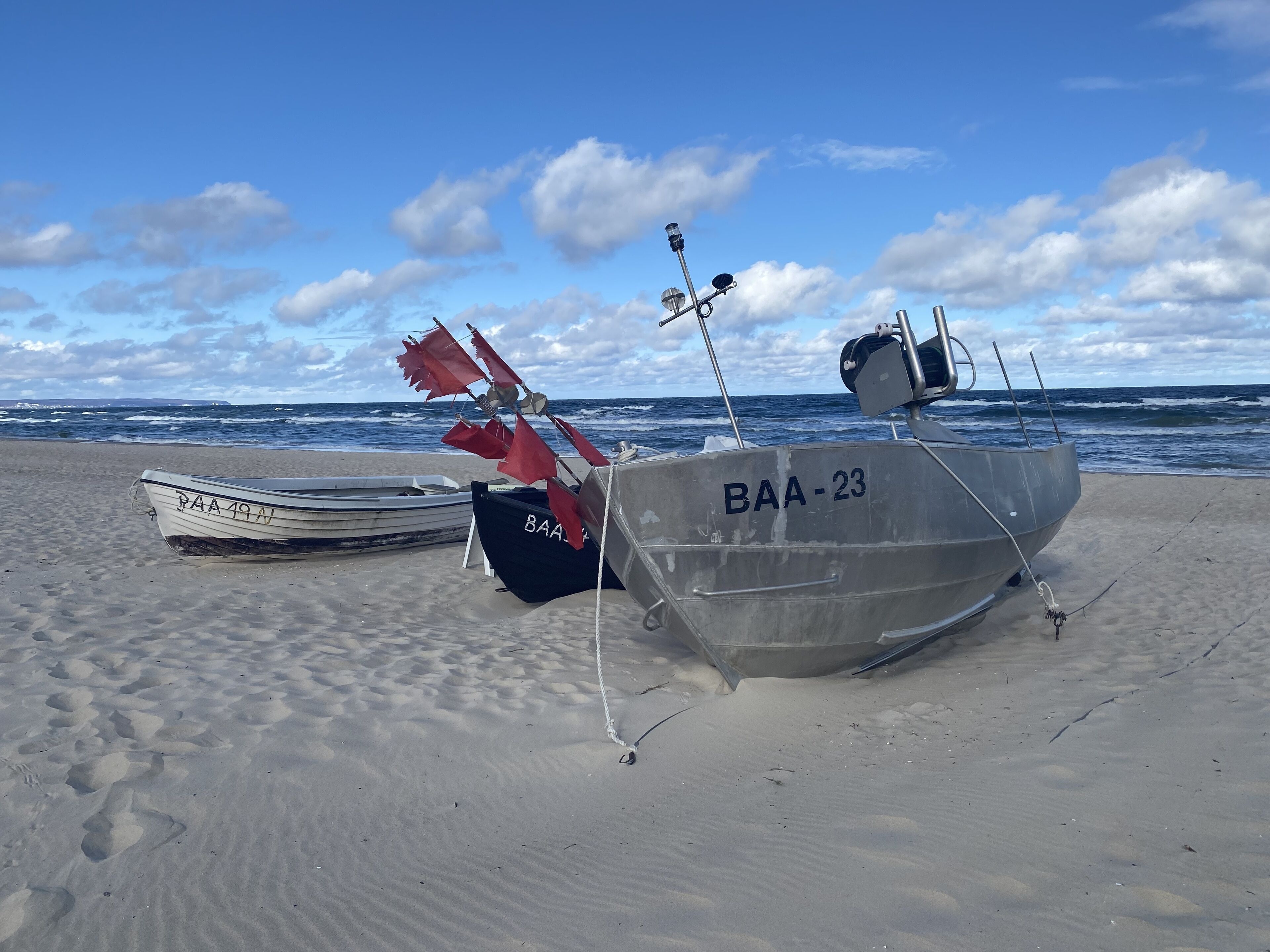 Dos barcos en una playa arenosa, con el océano al fondo.