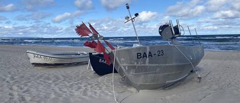 Dos barcos en una playa arenosa, con el océano al fondo.