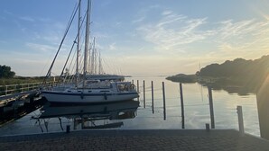 Un puerto deportivo con un velero amarrado, agua tranquila y cielo despejado.