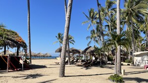 A beach with palm trees, thatched umbrellas, and lounge chairs. - Ocean view 1King Bedroom/2BA, kitchen, private balcony, sofa bed, beachfront (Puerto Vallarta)