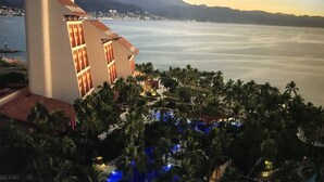 A resort with a pool area, palm trees, and a view of the sea and mountains. - Ocean view 1King Bedroom/2BA, kitchen, private balcony, sofa bed, beachfront (Puerto Vallarta)