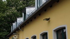 A yellow building with three windows, each with a flower box. - Hubertushöhe (Regensburg)