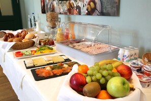 A buffet table with various food items including fruits, cheeses, meats, and pastries. - Hubertushöhe (Regensburg)