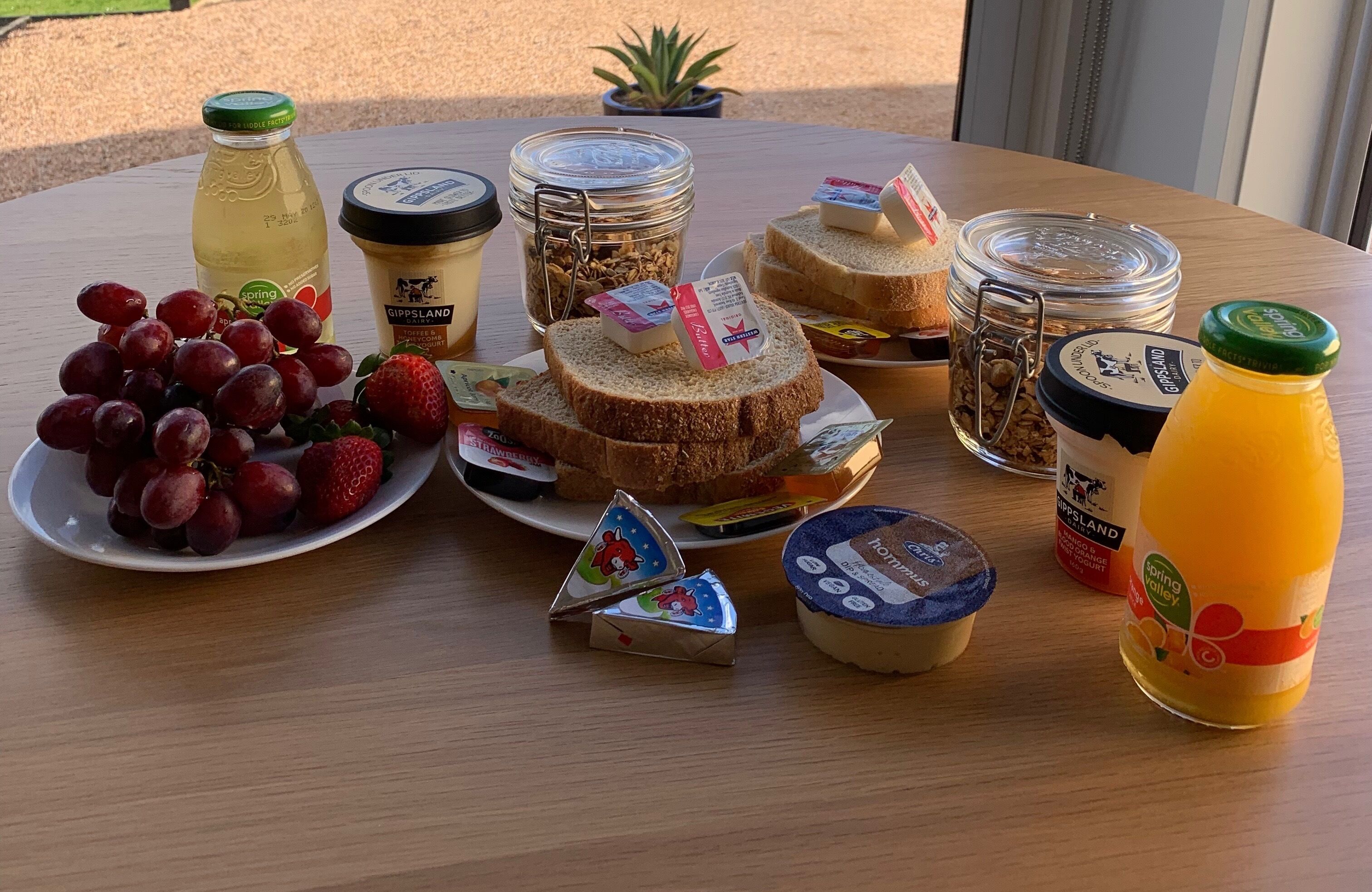 A table with various food items including grapes, strawberries, sandwiches, and condiments.