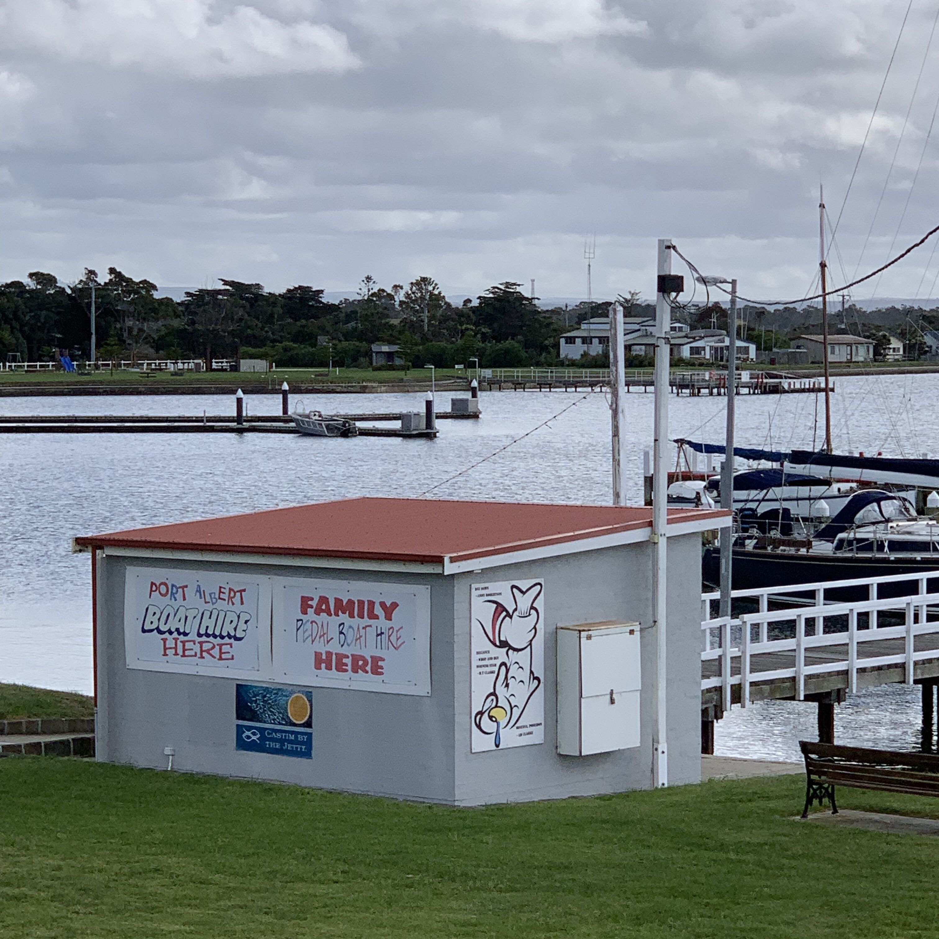 A small boat rental station with signs indicating family pedal boat hire and boat hire services.