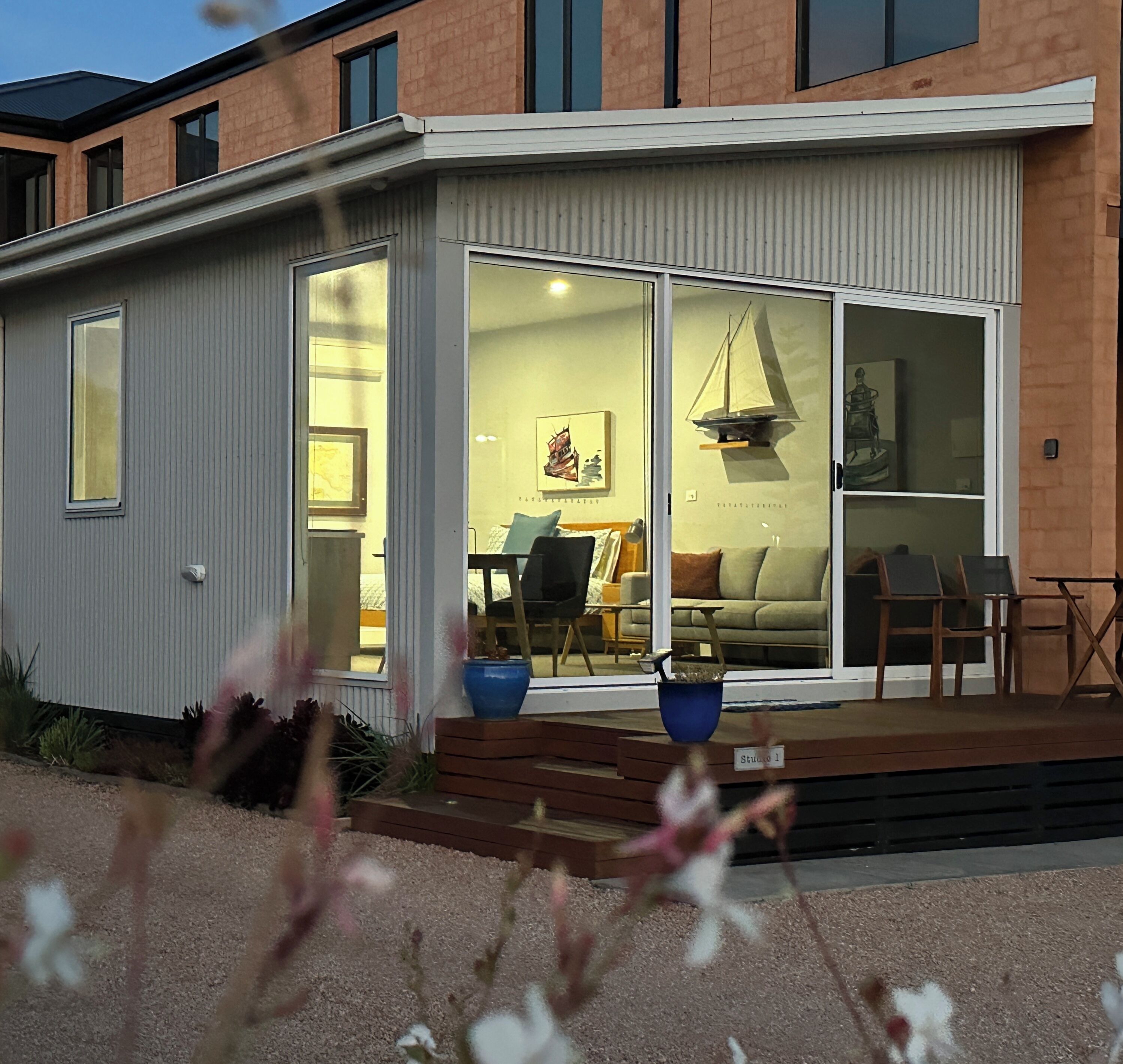 Een modern huis met een grote schuifglazen deur die uitkomt in een woonkamer.