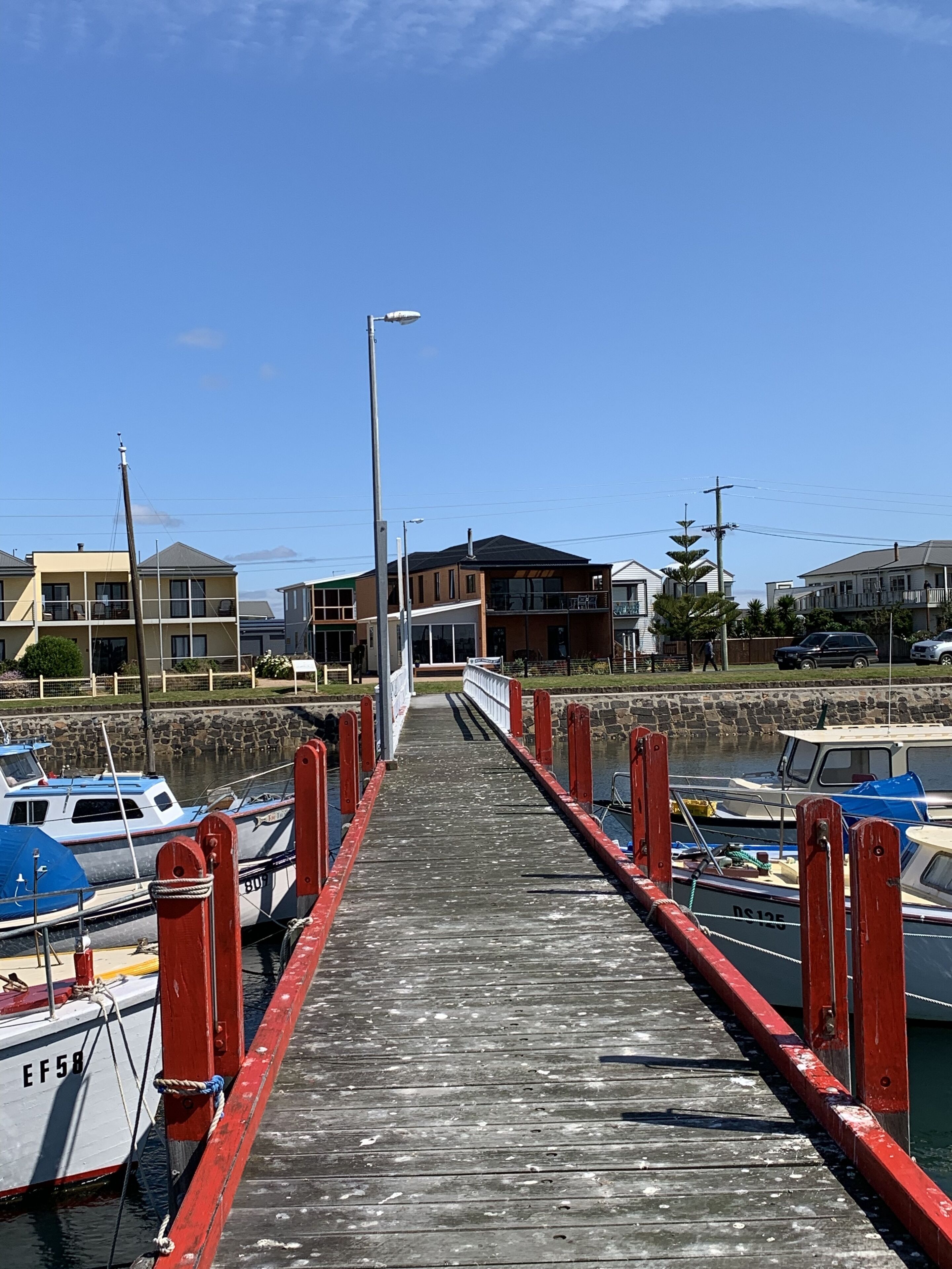 A wooden pier leading to a marina with boats docked on both sides.