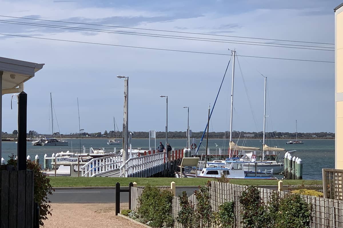A marina with boats docked, a pedestrian bridge, and a clear sky.