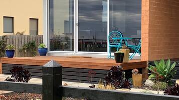 Een moderne patio met een schuifpui, een houten terras en diverse plantenpotten.