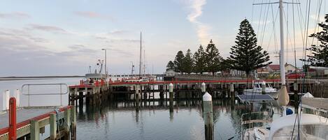 A marina with boats docked, a pier with a red railing, and a calm water body.