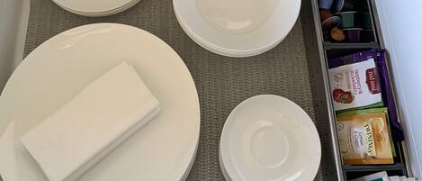 A drawer with neatly stacked white plates, a folded napkin, and various tea packets.