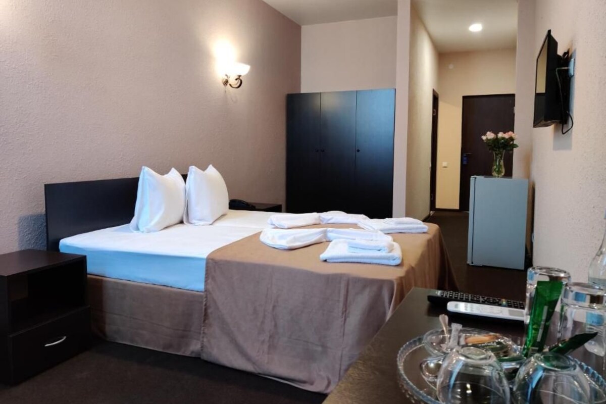 Een hotelkamer met een bed, nachtkastje en een spiegel.