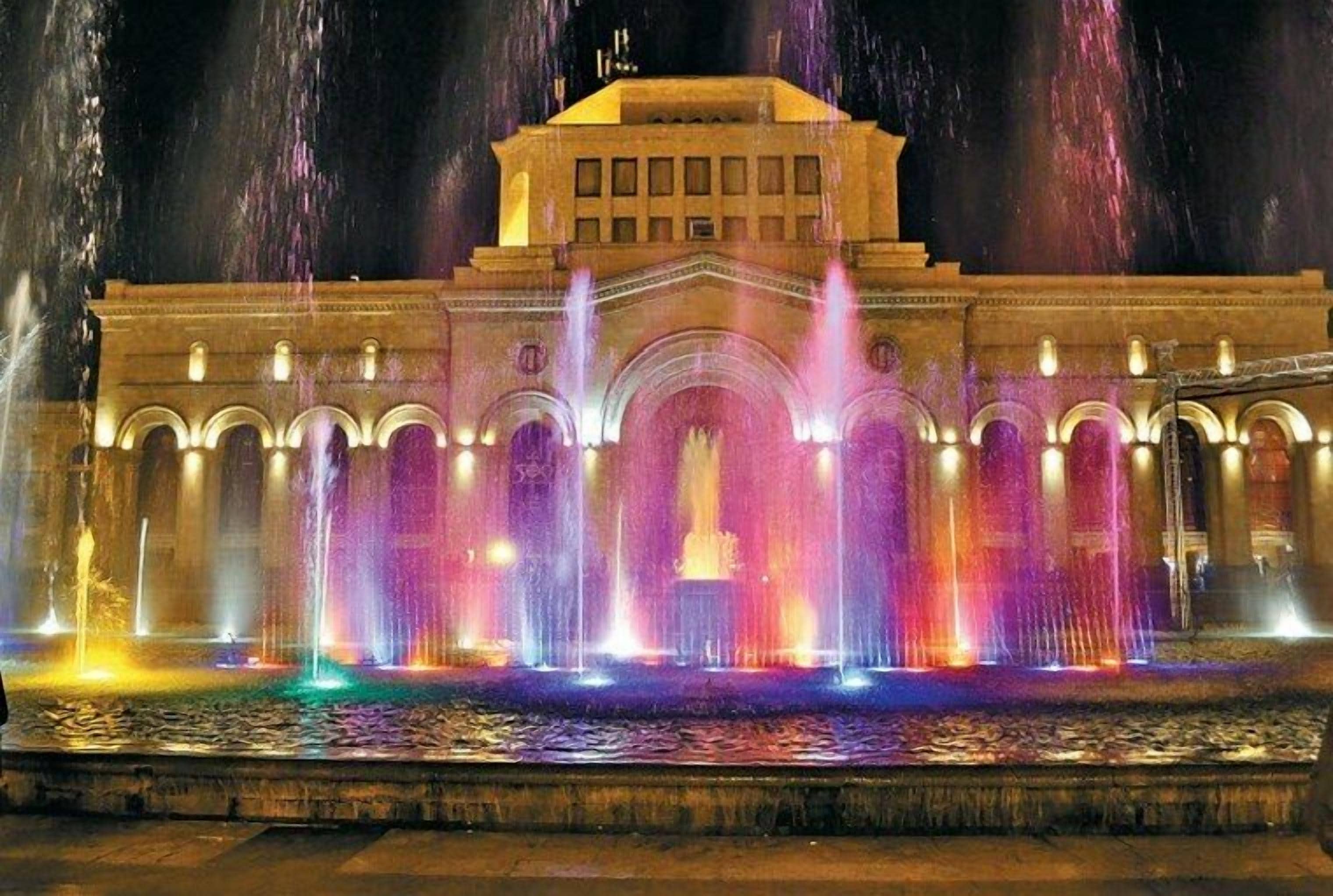 A building with a central archway and multiple fountains.