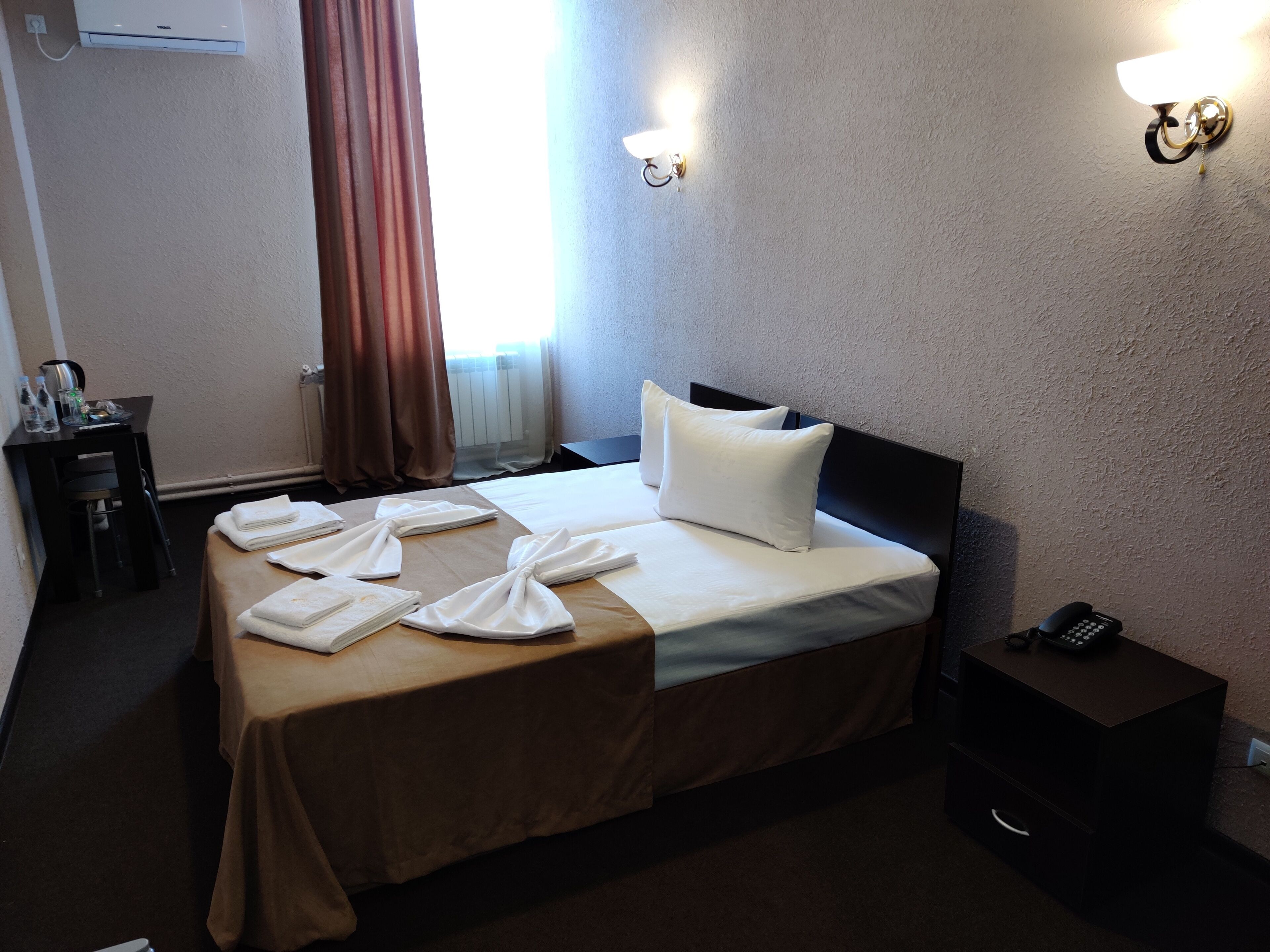 Une chambre d’hôtel comprenant un lit, une table de chevet et un bureau avec une chaise.