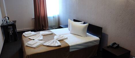 Une chambre d’hôtel comprenant un lit, une table de chevet et un bureau avec une chaise.