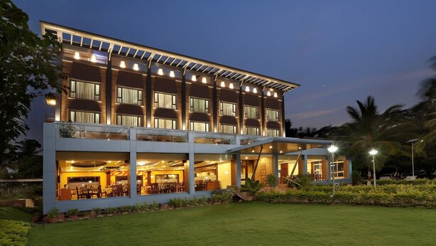 A modern hotel with a two-story structure, outdoor dining area, and a well-lit entrance. - Mayur aaditya resort (Dharwad)