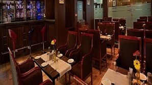 A restaurant with a bar area, multiple dining tables, and chairs. - Mayur aaditya resort (Dharwad)