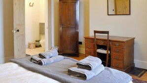 Una camera da letto con un letto, una cassettiera in legno, una sedia e un armadio.