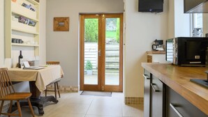 Una cucina con tavolo da pranzo, sedie, televisione e libreria.