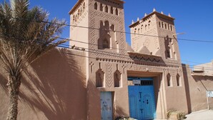 A traditional building with two towers and a blue door. - Gîte Kasbah La palmeraie (Skoura)