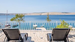 Un balcon avec deux chaises, une piscine et une vue sur la mer et les collines.