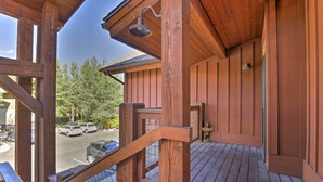A wooden deck with a railing, a hanging light fixture, and a view of parked cars and trees. - Riverfront Silverthorne Condo Near Skiing! (Silverthorne)