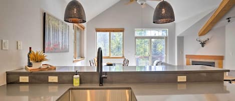 A modern kitchen with a large island, pendant lights, and a ceiling fan.