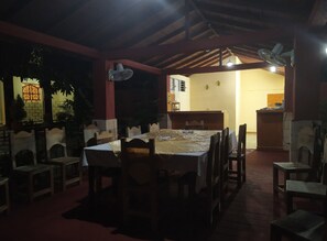 A dining area with a table set for four, surrounded by chairs, under a wooden ceiling with exposed beams. - Hostal Yanelis & Harol (Trinidad)