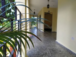 A corridor with a plant in the foreground, a tiled floor, and a door at the end. - Hostal Yanelis & Harol (Trinidad)