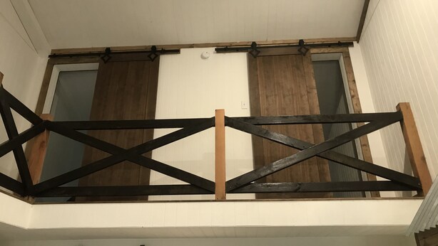 A room with a sloped ceiling, wooden beams, and a window with blinds.