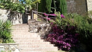 Un escalier en pierre mène à un bâtiment dont le mur est en pierre et qui est entouré d’une clôture en bois.