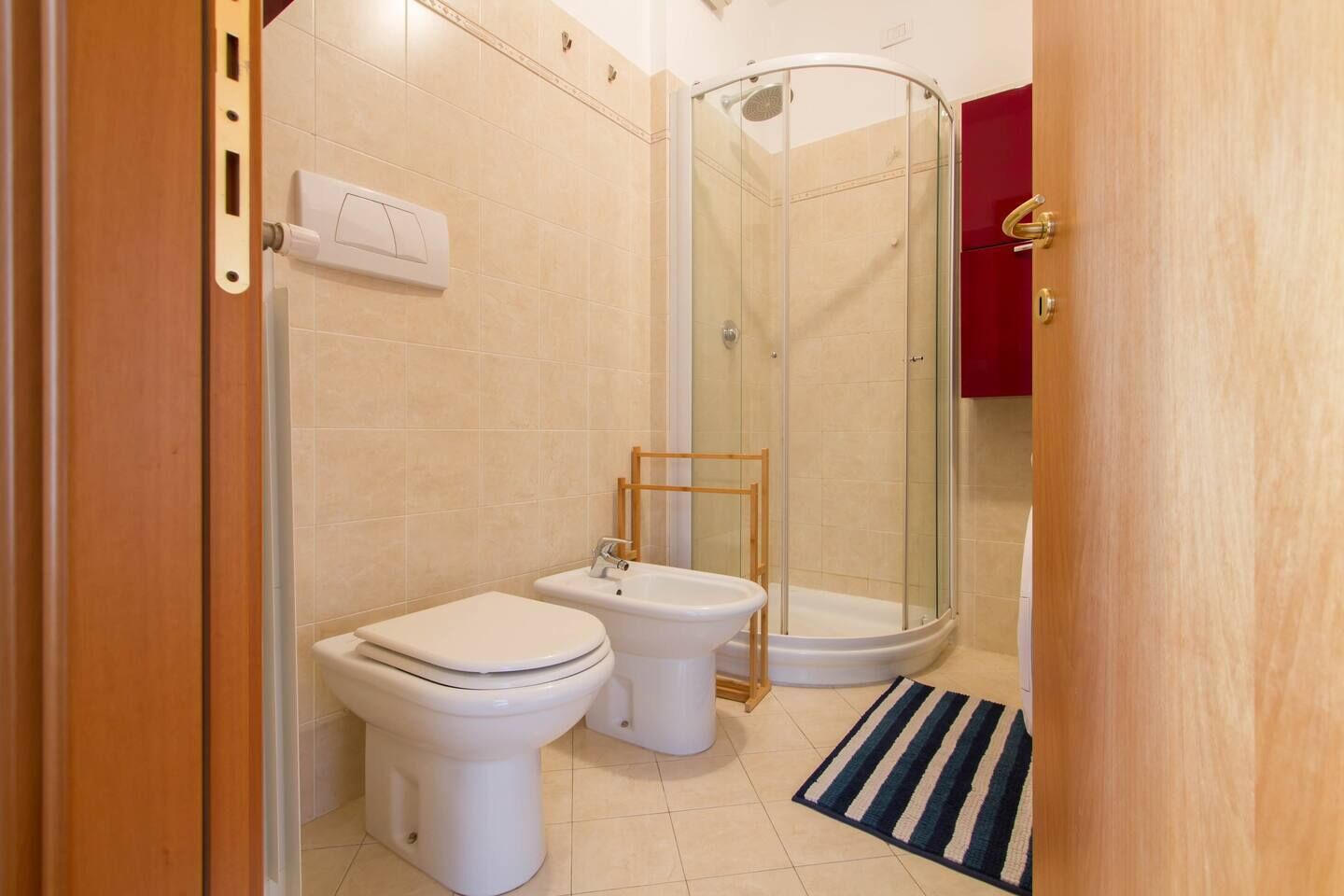 A bathroom with two toilets, a bidet, and a glass-enclosed shower.