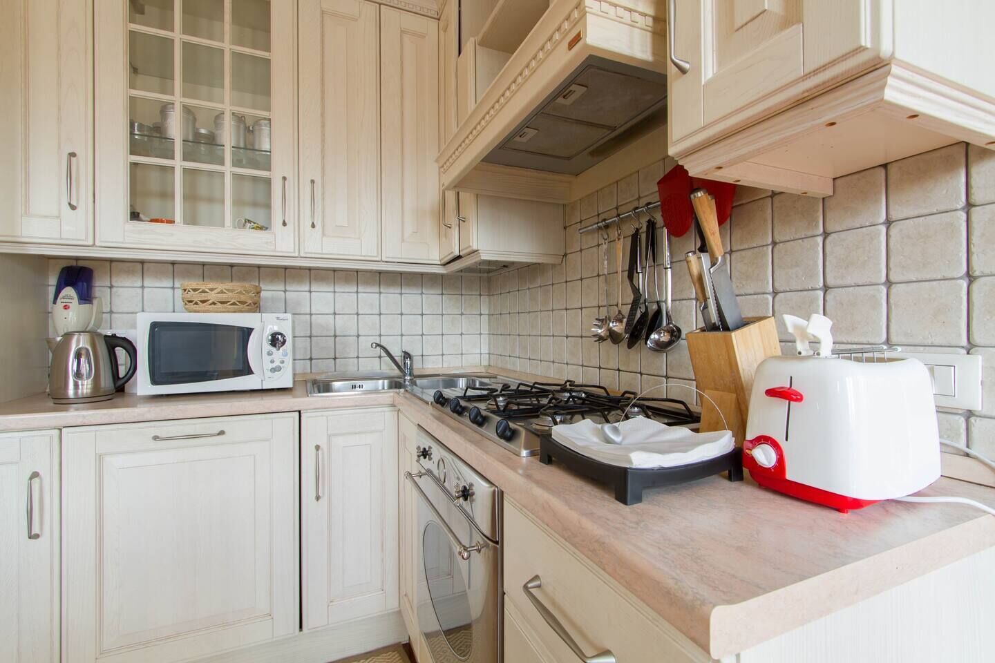 Una cocina con armarios blancos, microondas, estufa a gas y tostadora.