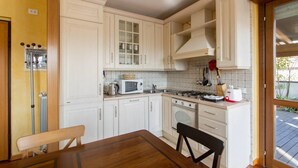A compact kitchen with white cabinetry, a microwave, a stove, and a dining table with chairs. - Bright house with 2 bedrooms & a unique terrace (Bergamo)