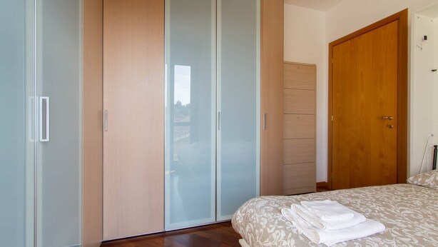 A bedroom with a bed, a wardrobe, and a door. - Bright house with 2 bedrooms & a unique terrace (Bergamo)