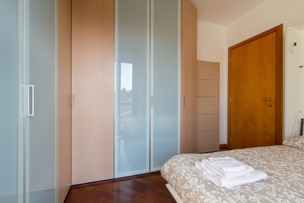 Een slaapkamer met een bed, een kledingkast en een deur.