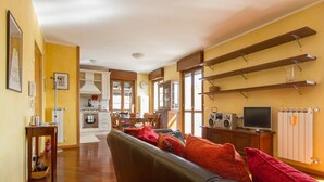 A spacious living room with a sofa, a dining area, and a kitchen in the background. - Bright house with 2 bedrooms & a unique terrace (Bergamo)