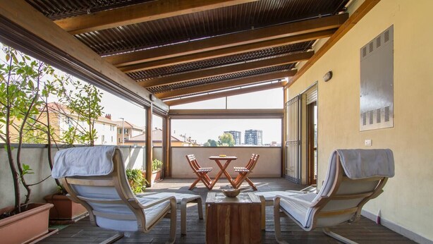 A covered outdoor patio with a table and four lounge chairs, a view of buildings in the background, and a wooden ceiling. - Bright house with 2 bedrooms & a unique terrace (Bergamo)