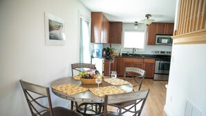 A dining area with a round table, four chairs, and a fruit bowl.