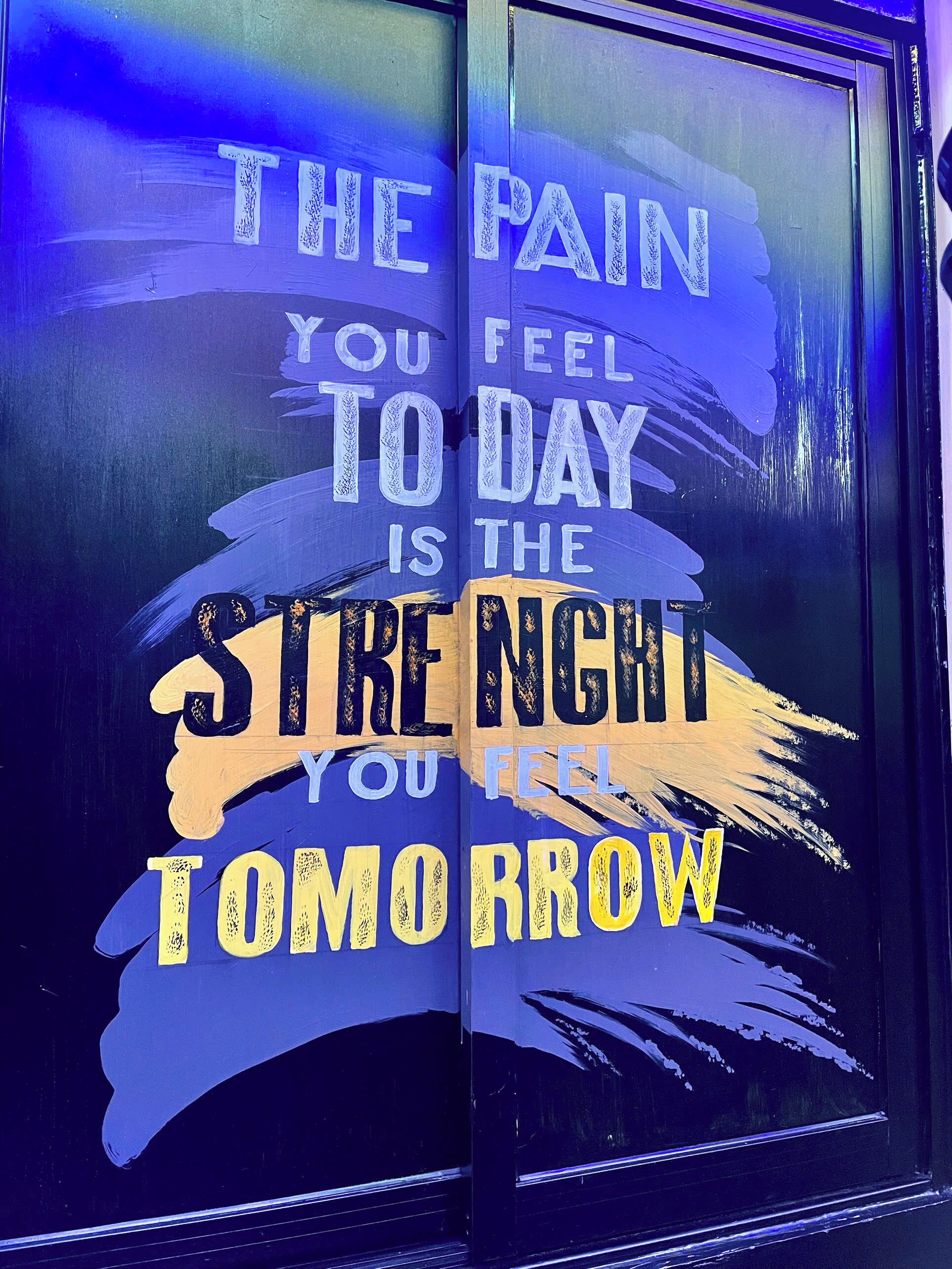 Una frase motivacional en una puerta de cristal con diseño de pinceladas.