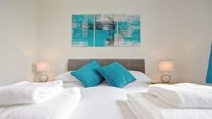 A hotel room with a large bed, two pillows, two bedside lamps, and a wall art piece. - Rockworks Chalets No.3 - UK7042 (Holm, near Kirkwall)