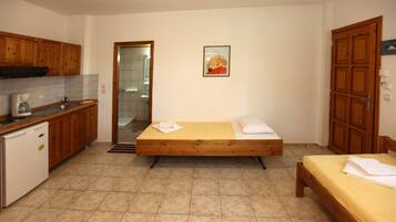 Una habitación compacta con cama, un pequeño kitchenette y un baño visible a través de una puerta abierta.