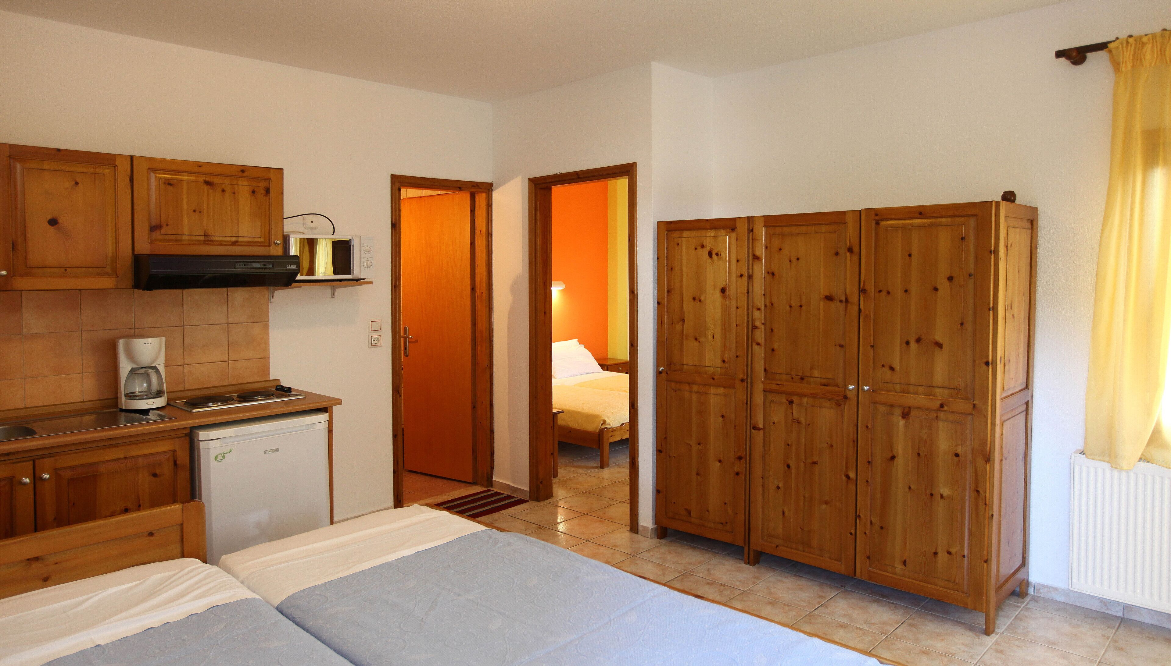 Habitación pequeña con cama, kitchenette y armario.
